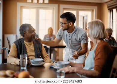 Young healthcare worker talking to seniors during lunch at nursing home. - Powered by Shutterstock