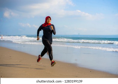 Young Healthy And Active Runner Muslim Woman In Islam Hijab Head Scarf Running And Jogging On The Beach Wearing Traditional Arab Sport Clothes In Fitness Workout And Weight Loss Concept