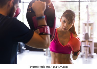 Young healthy Asian woman doing boxing with trainer at the gym, sport and recreation activity concept.