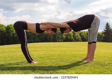 Young Healthy Couple Doing Acrobatic Yoga Exercise In Park