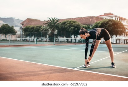 Young Healthy Girl Doing Stretching Exercises On Tennis Court. Sportswoman Doing Warmup Workout Outdoors.