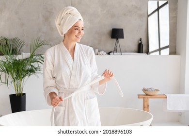 Young healthy serene woman girl relaxing in bathrobe and spa towel after having bath shower at home. Beauty treatment, rest and body care procedures.