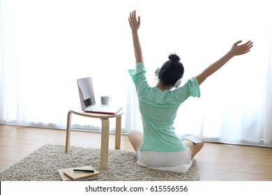 Young healthy woman back view at modern home sitting on floor with computer and coffee cup in front of window relaxing in her living room working on internet, Wake up. - Powered by Shutterstock