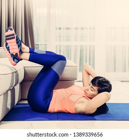 Young healthy woman exercising on mat in living room, image with warm vintage toning