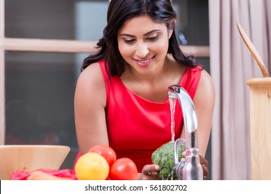 Young healthy woman washing fresh vegetables in the kitchen at home - Powered by Shutterstock