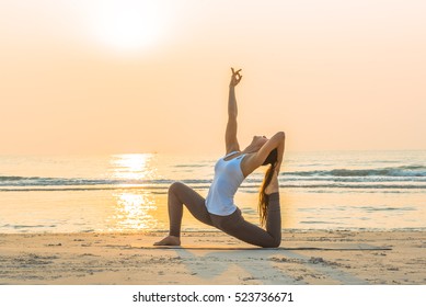 Young healthy Yoga woman workout yoga pose on the beach at sunrise, benefits of natural environments for physical, spiritual, healthy, relaxing concept.  - Powered by Shutterstock