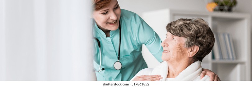 Young Helpful Doctor Taking Care Of Senior Woman In Nursing Home