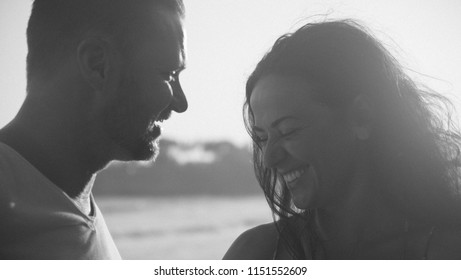 A Young Heterosexual Couple Shares A Genuine Laugh While At The Beach In This Black And White Photo.