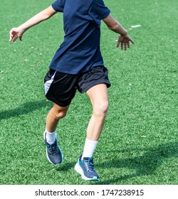 A Young High School Athlete Is Performing Kereoke Bounding Drill While Warming Up On A Turf Field During Sports Team Practice.