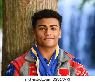 Young High School Senior Athlete With Letter Jacket And Medals Posing For Senior Photos