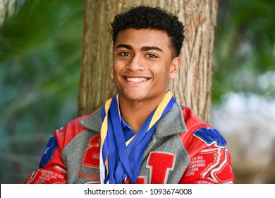 Young High School Senior Athlete With Letter Jacket And Medals Posing For Senior Photos