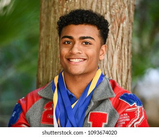 Young High School Senior Athlete With Letter Jacket And Medals Posing For Senior Photos