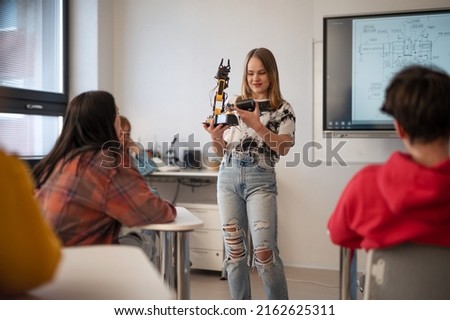 Young High school student is presenting her robotic project in classroom