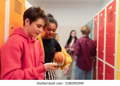 Young high school students standing near locker in campus hallway talking and using smartphone. - Powered by Shutterstock