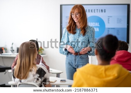Young High school teacher giving marketing lesson to students in classroom