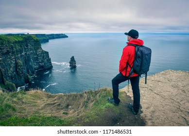 Young hiker with a backpack standing at the cliffs of Moher located at the edge of the Burren region in County Clare, Ireland. - Powered by Shutterstock