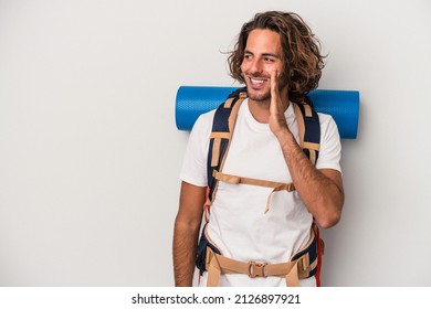 Young hiker caucasian man isolated on gray background is saying a secret hot braking news and looking aside - Powered by Shutterstock