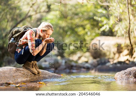 young hiker drinking stream water in mountain