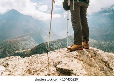 Young hiker female standind in cliff edge and enjoying the Imja Khola valley during an Everest Base Camp (EBC) trekking route near Tengboche. Hiker using trekking poles and weared hard trekking boots.