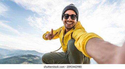 Young hiker man taking selfie portrait on the top of mountain - Happy guy smiling at camera - Hiking and climbing cliff