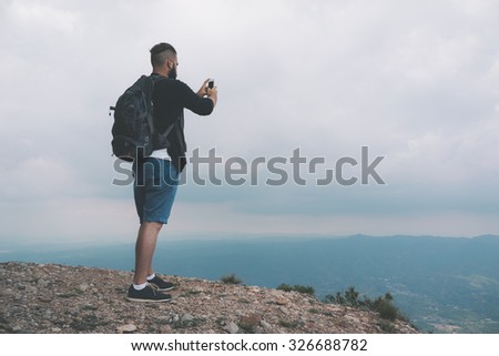 Young hiker taking picture with phone camera of landscape