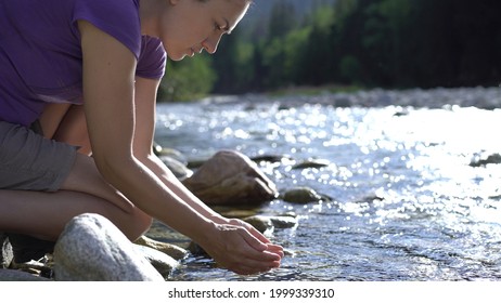 Young hiker woman drinking stream water in the mountains, Slovakia, High Tatras, Bielovodska valley 
