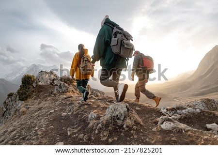 Young hikers with backpacks walks in mountains at sunset