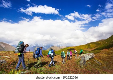 Young hikers trekking in Svaneti, Georgia. Shkhara mountain in the background. Amazingly beautiful WORLD. Fantastic sky background with blue clouds.
