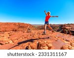 Young hiking girl jumping at Kings Canyon. Enjoying in Red Center Outback. Jumper among sandstone formations in Watarrka National Park. King Canyon Rim Walk at sunset. Northern Territory, Australia.