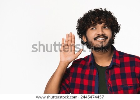 Young Hindi man listening to rumors isolated over white background. Cheerful Indian boy in casual outfit hearing news, new ideas with copyspace
