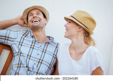 Young Hip Couple Laughing On Bench On A Sunny Day In The City