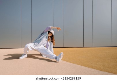 Young hip hop girl in oversize outfit wearing dancing into music minimalistic urban background. Hip-hop queen. Breakdancer woman. minimalistic  - Powered by Shutterstock