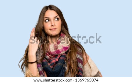 Young hippie woman with fingers crossing and wishing the best over isolated blue background
