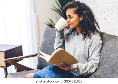 Young Hipster African American Black Woman Relaxing Reading The Paper Book Work Study And Looking At Page Magazine While Sitting On Couch At Home