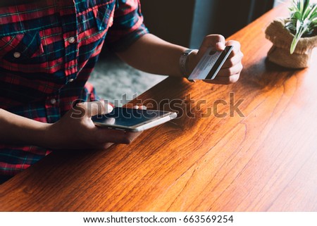 young hipster Asian woman using portable smart phone while sitting in the coffee shop. Young beautiful girl using a smart phone  to bill pay on the internet.