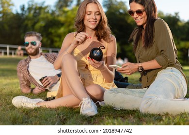 joven hipster compañía de amigos que se divierten juntos en el parque sonriendo escuchando música en un pequeño altavoz inalámbrico, temporada de estilo de verano, tomando café