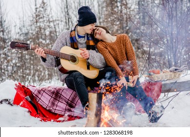 Young Hipster Couple In Love Hugging Near The Bonfire. Winter Weather. Romantic Love Story