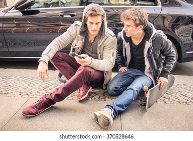 Young Hipster Fashion Brothers Having Fun Using Smartphone - Best Friends Sharing Time With Smart Phone - Everyday Life Moment With Modern Device - Light Vintage Filtered Look With Soft Focus On Faces