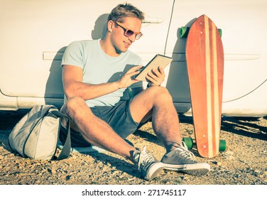 Young Hipster Fashion Guy With Computer Tablet Sitting Next His Car During Road Trip - Concept Of New Trends And Technology Mixed With Vintage Lifestyle - Traveler Man On Retro Nostalgic Filtered Look