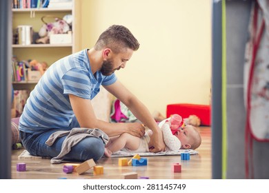 Young Hipster Father Changing Nappy To His Little Baby Daughter