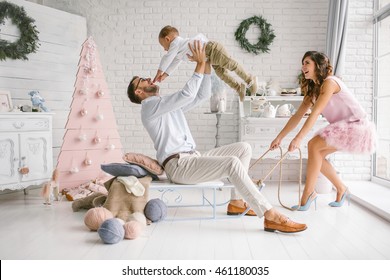 Young hipster father, mother and baby having fun with sled in white decorated studio