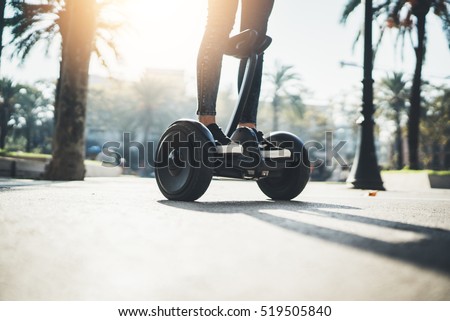 Young hipster girl driving on hoverboard at sunny park, active woman balancing on modern electric segway, alternative transport concept, ecology and environment concept, flare light
