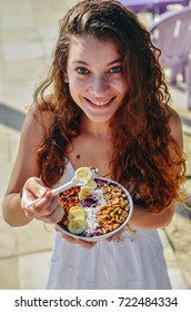 Young Hipster Girl, Holding A Acai Berry Bowl, With Spoon Banana, Nut, Tapioca And Granola