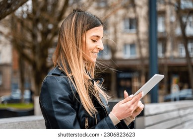 Young hipster girl holding pc tablet in the city.Traveler woman using tablet.reading guide book map on tablet computer pc,using mobile internet.Female writes text message or content. - Shutterstock ID 2306823623