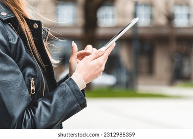 Young hipster girl holding pc tablet in the city.Traveler woman using tablet.reading guide book map on tablet computer pc,using mobile internet.Female writes text message or content. - Shutterstock ID 2312988359