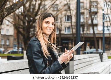 Young hipster girl holding pc tablet in the city.Traveler woman using tablet.reading guide book map on tablet computer pc,using mobile internet.Female writes text message or content. - Shutterstock ID 2324633237