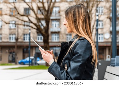 Young hipster girl holding pc tablet in the city.Traveler woman using tablet.reading guide book map on tablet computer pc,using mobile internet.Female writes text message or content. - Shutterstock ID 2330113567