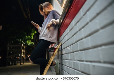 Young Hipster Girl With Longboard Using Phone Outdoors