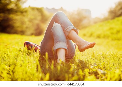 Young hipster girl lying on the grass at sunset summer time - Powered by Shutterstock