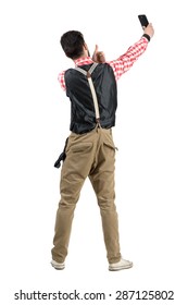 Young Hipster Male Taking Selfie With Thumbs Up Rear View. Full Body Length Portrait Isolated Over White Studio Background. 